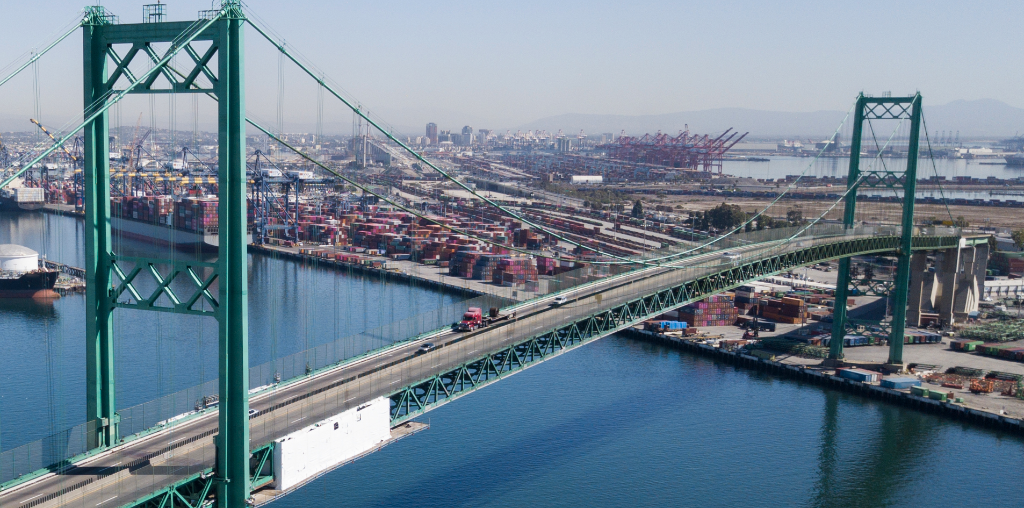 Aerial view of the green Vincent Thomas Bridge crossing the Port of Los Angeles, with water, cranes and container terminals
